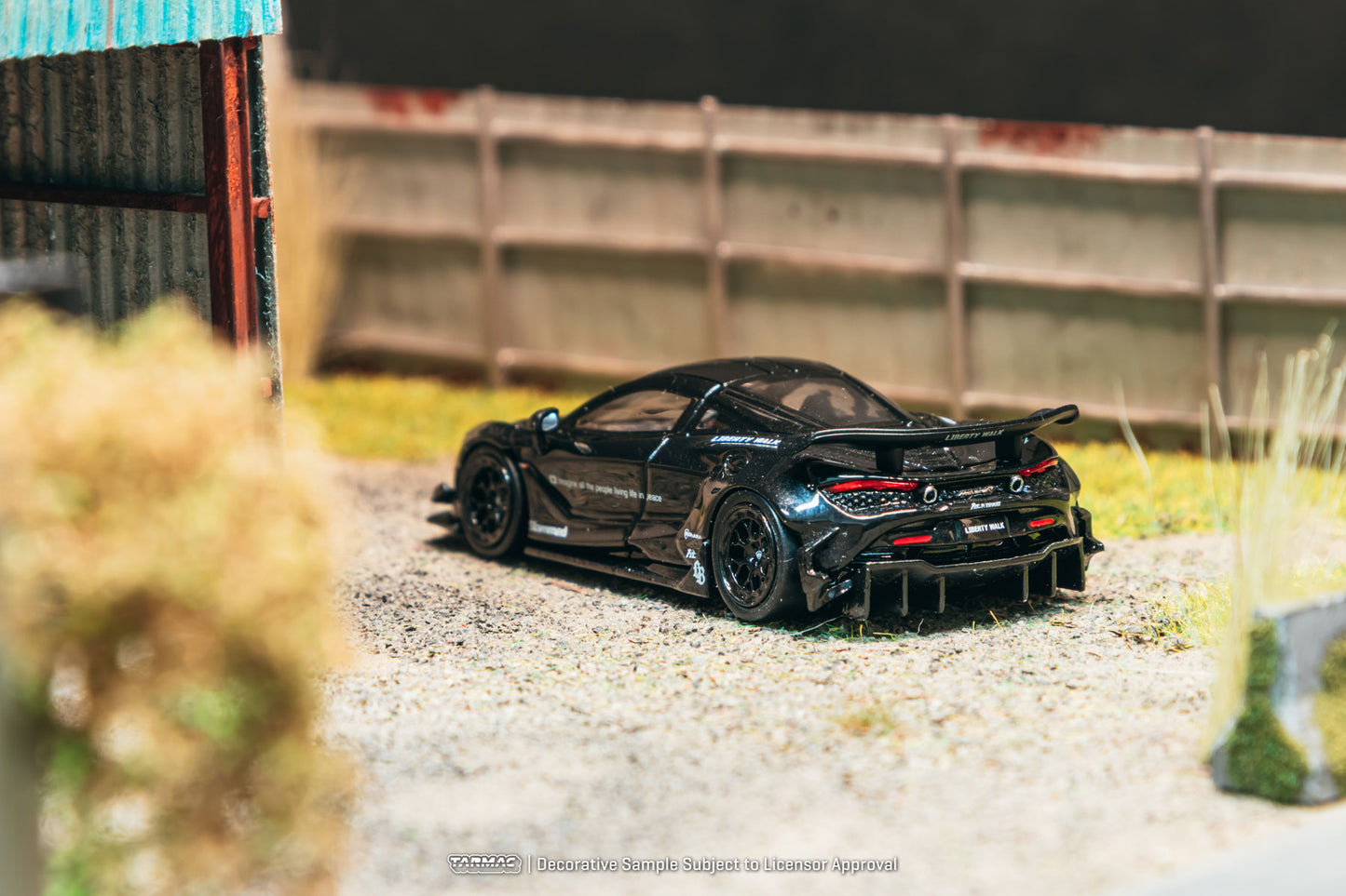 Black sports car model on a gravel surface with a blurred background