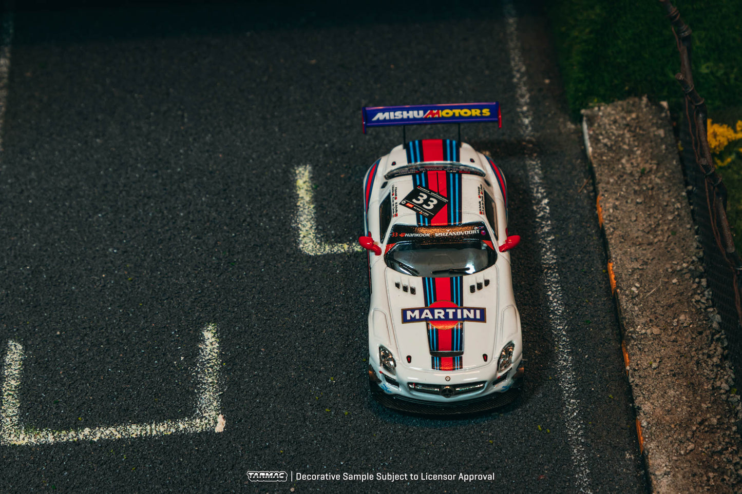 White race car with red and blue stripes on a track, featuring Martini branding.