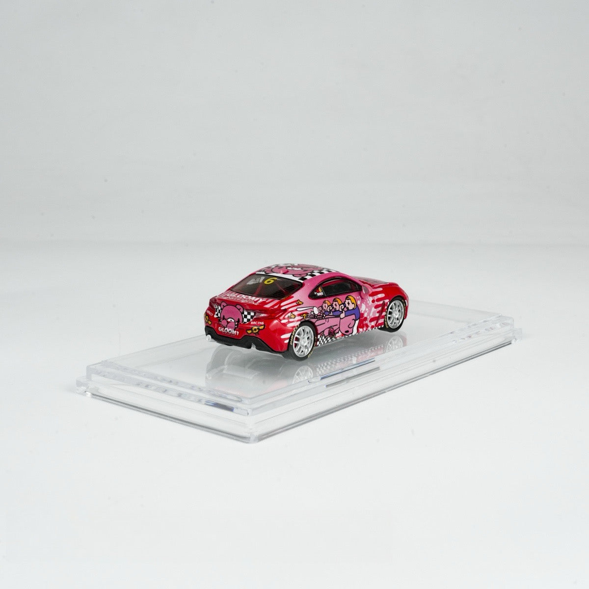 A red toy car with cartoon designs, featuring pink characters and checkerboard patterns, displayed on a clear stand against a simple white background.