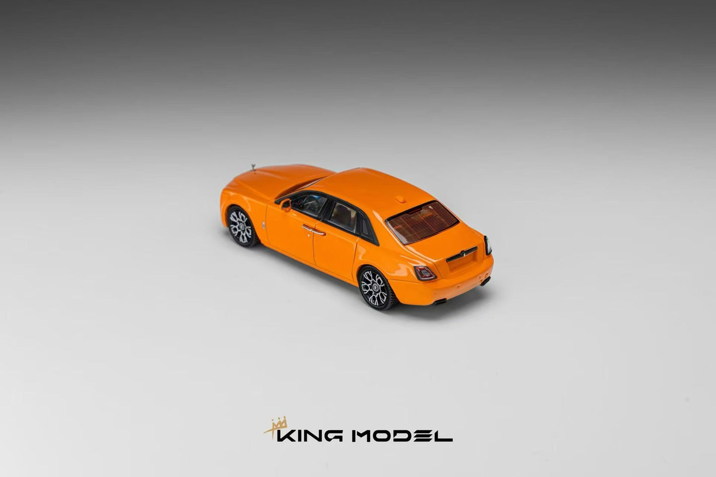 An orange model car, resembling a luxury sedan, shown from a three-quarters rear angle on a gray gradient background with the brand name 'KING MODEL' at the bottom.