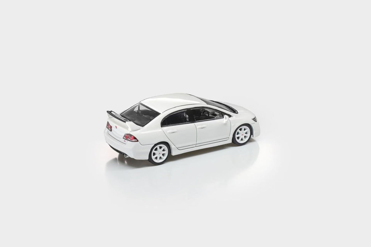 A white diecast model of a Honda Civic sedan with a rear spoiler, shown from a three-quarters rear angle on a clean white background.