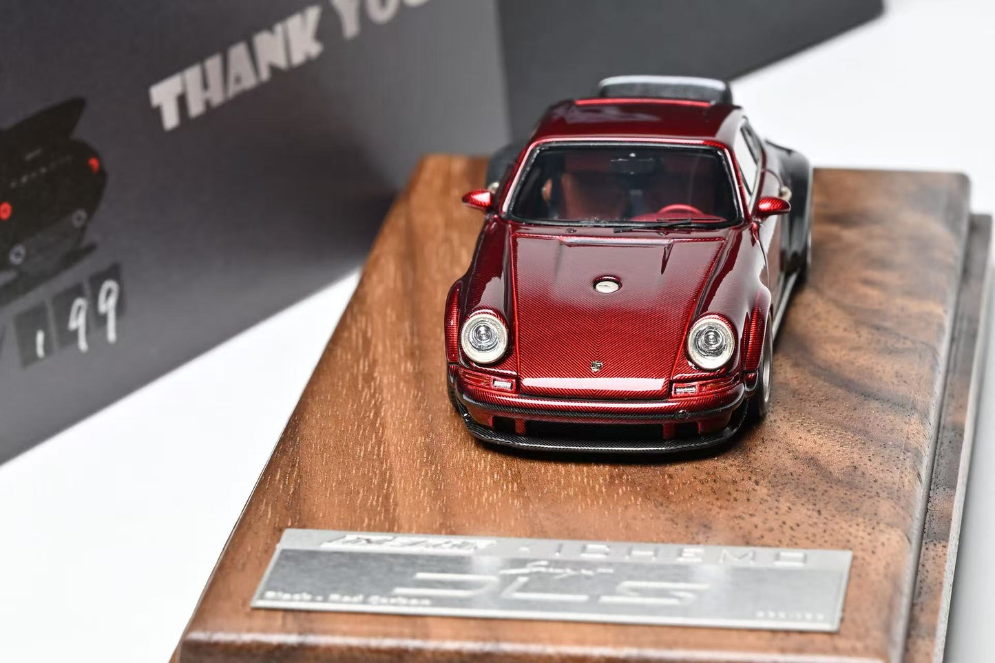 Red model car on a wooden display stand with a 'THANK YOU' card in the background.