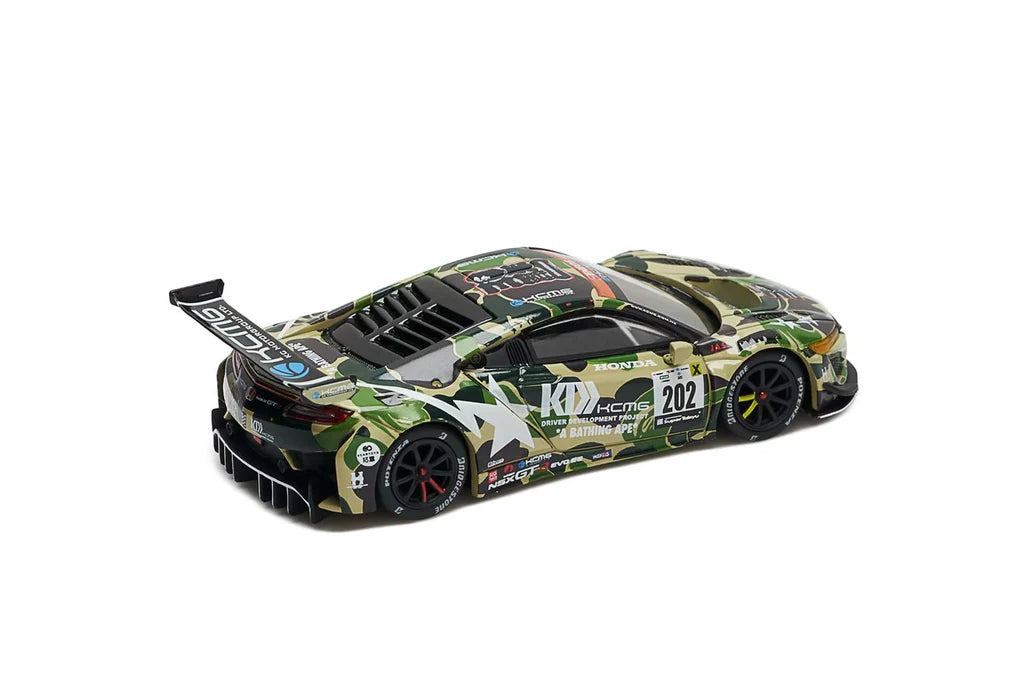 Camouflaged sports car model with a wide rear wing, black wheels, and racing decals including number 202, set against a white background.