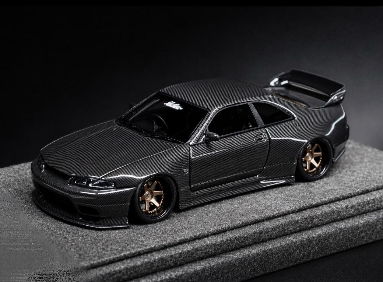 A dark gray carbon-fiber replica model of a Nissan Skyline R33 GT-R, displayed on a textured gray platform against a dark studio background.