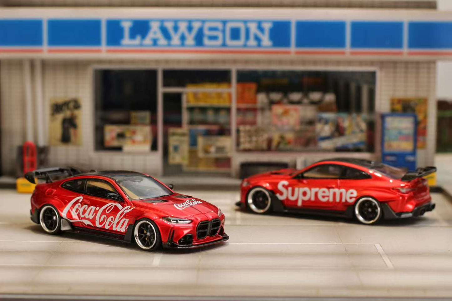 Two red sports cars with brand logos in front of a Lawson store.