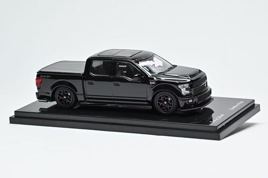 Black Ford Shelby F150 model truck on a display stand with a white background