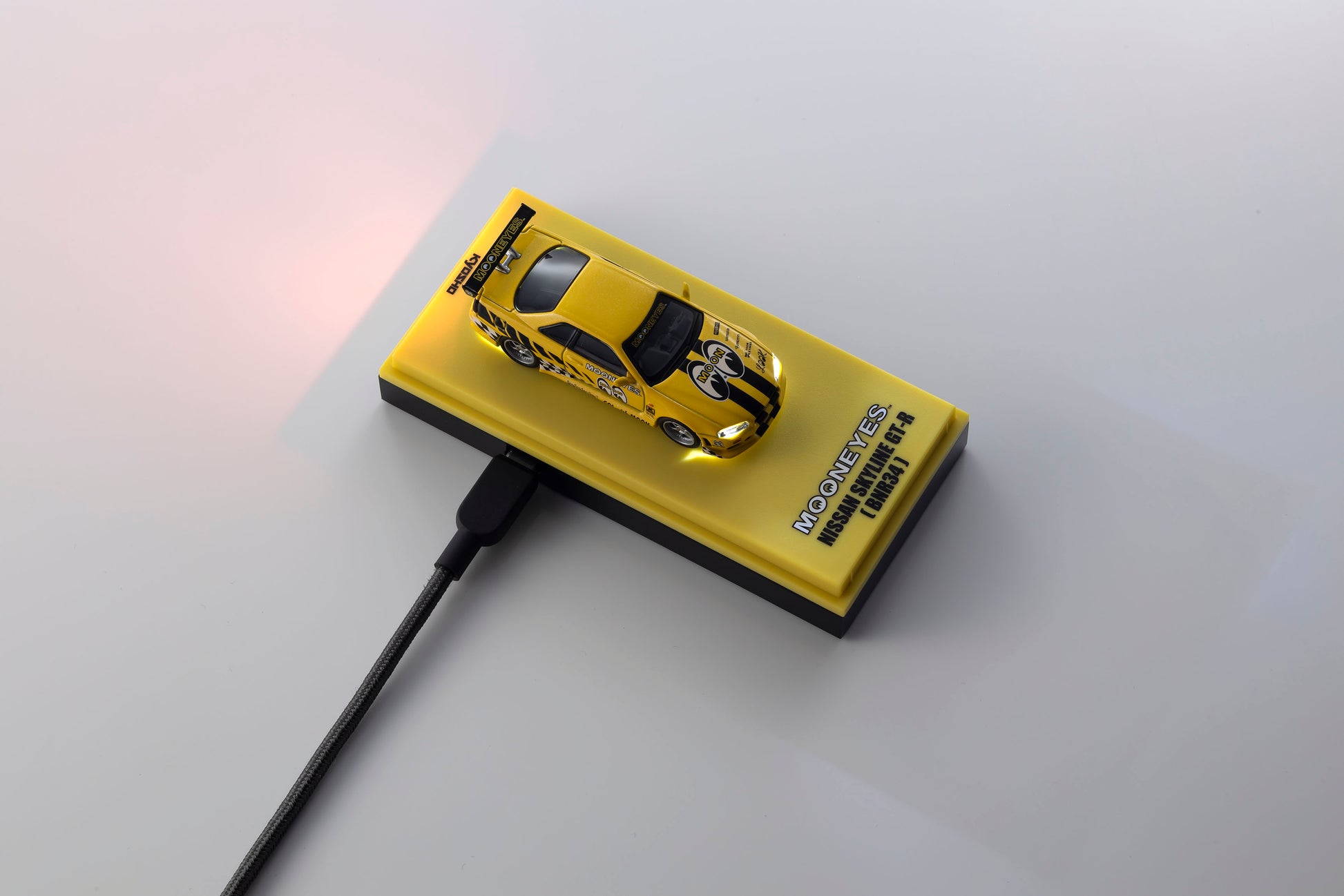 A yellow rectangular magnetic storage drive with a small yellow race car graphic on top, shown on a light gray background with a black cable plugged in. The drive features the text 'MICHAEL DE JAGUAR C3'.