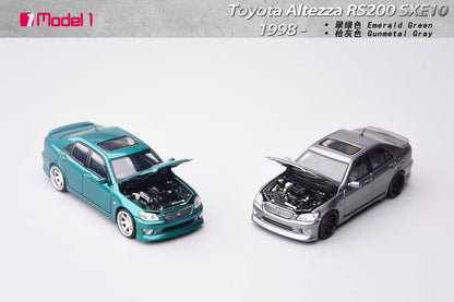 Two model cars, one teal and one gray, on a white background with text indicating 'Toyota Altezza RS200 SXE10' and '1998'.