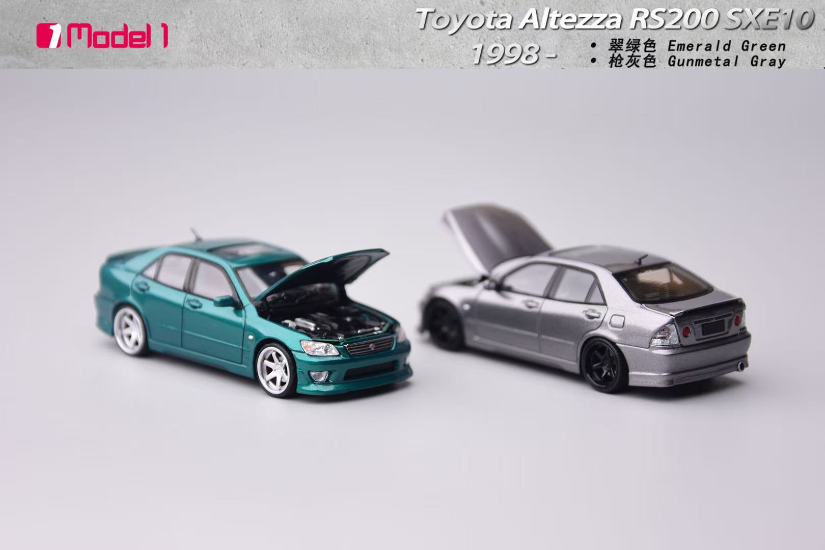 Two model cars, one teal and one silver, on a light gray background with text indicating 'Toyota Altezza RS200 SXE10' and '1998'.