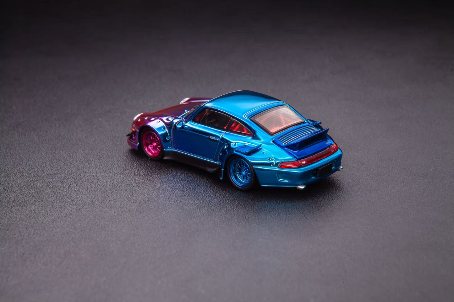 Blue toy car with red accents on a gray surface