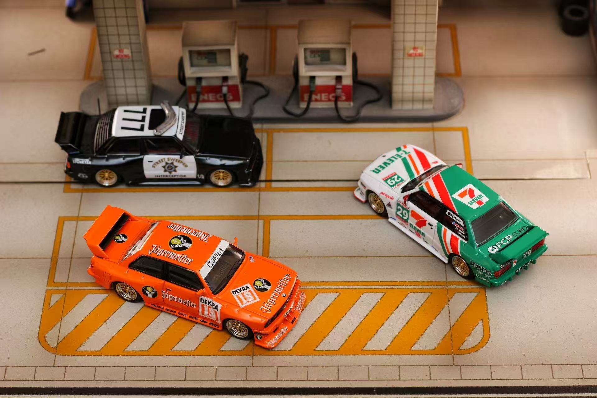 Three toy cars on a tiled floor with a gas station model in the background