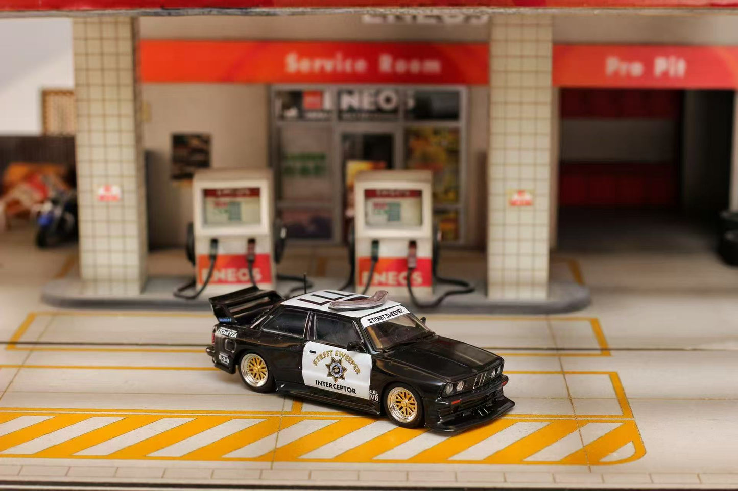 Model car on a miniature gas station platform with 'NEO' branding.