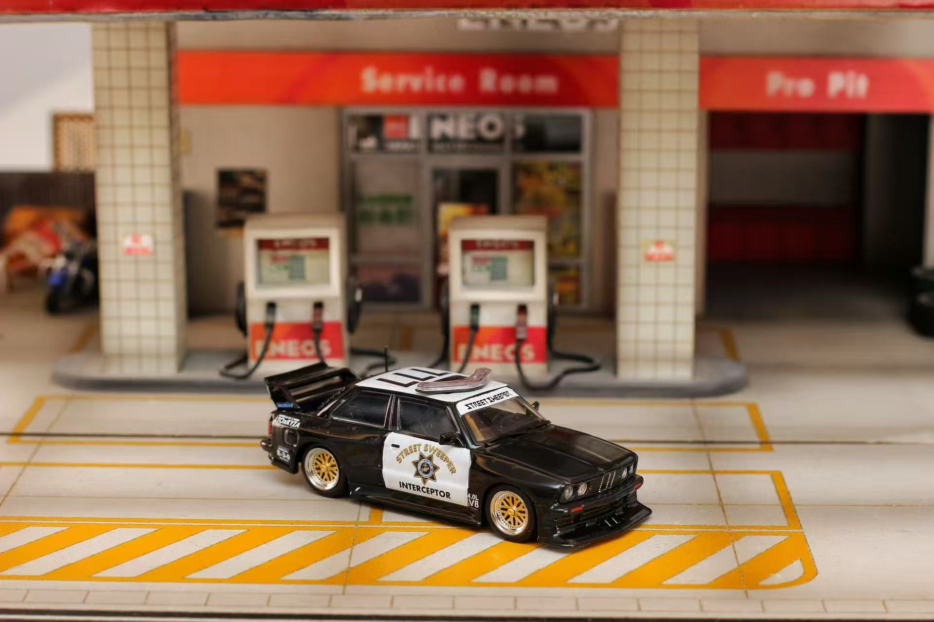 Model car on a miniature gas station platform with 'NEO' branding.