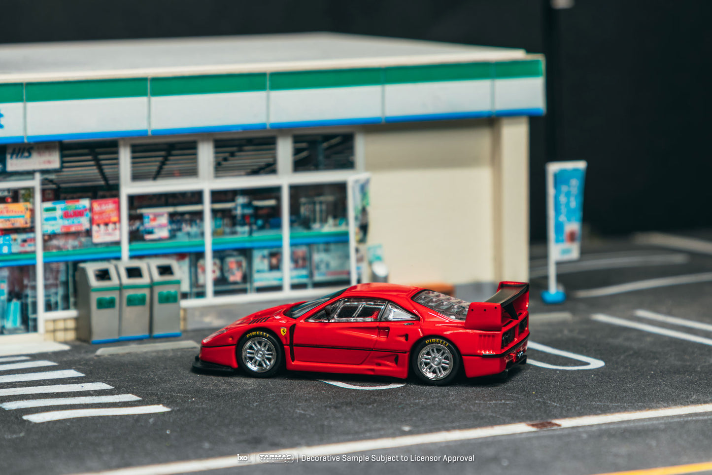 Red sports car model on a miniature street with a store in the background