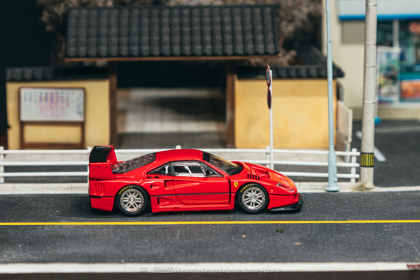 Red toy car on a miniature street with buildings in the background