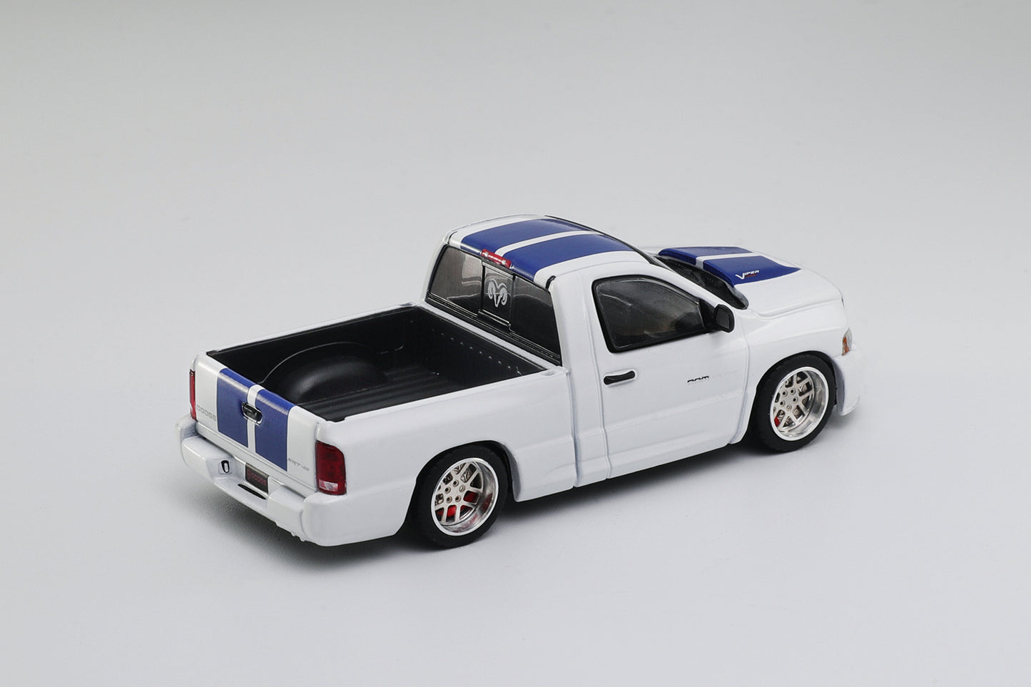 Model truck with a white body, black bed, and blue and red stripes on a gray background