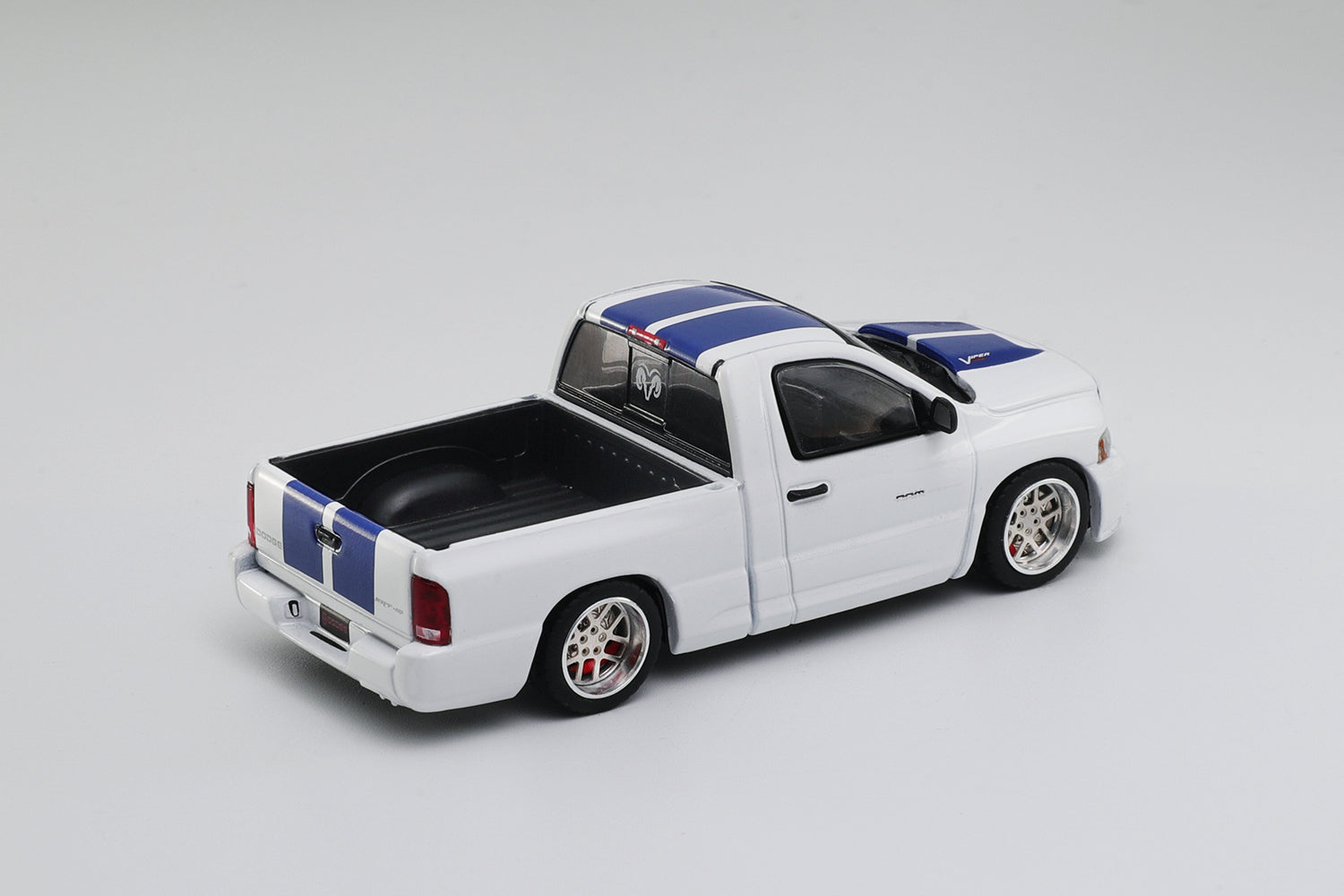 Model truck with a white body, black bed, and blue and red stripes on a gray background