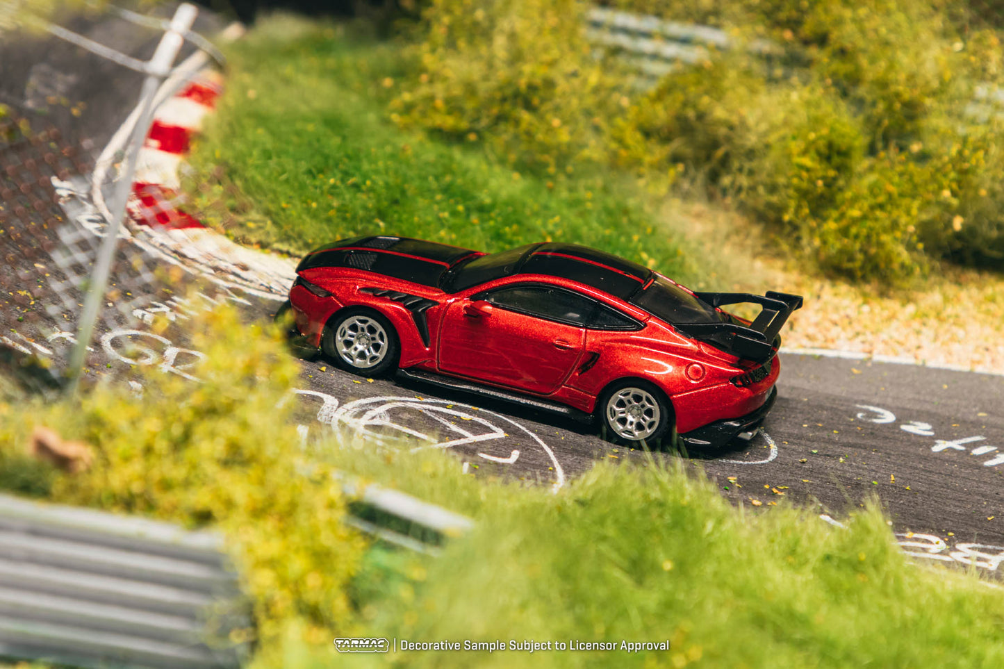 Red sports car on a miniature race track with greenery around