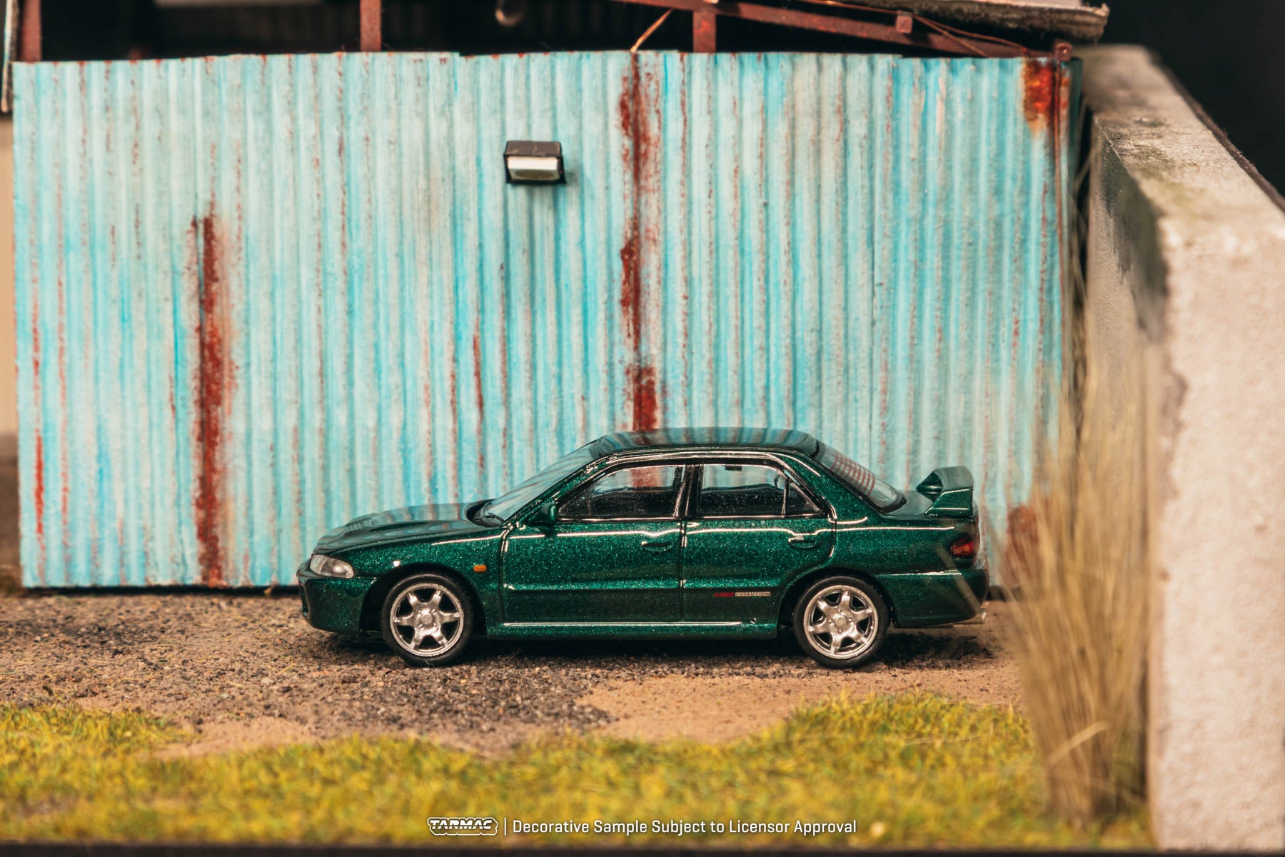 Green car parked in front of a rusty corrugated metal wall