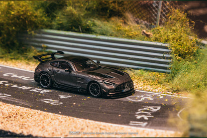 Model car on a miniature race track with greenery and a fence in the background