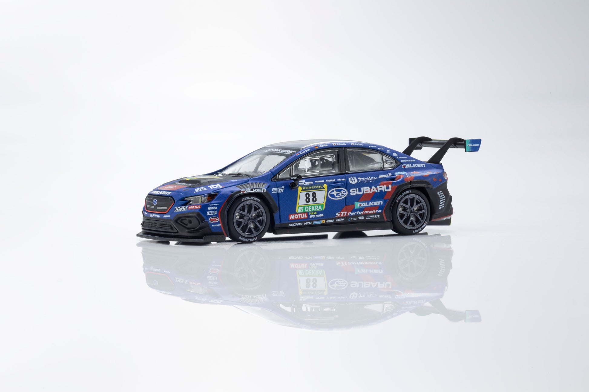 Model car of a Subaru race car on a reflective surface with a white background