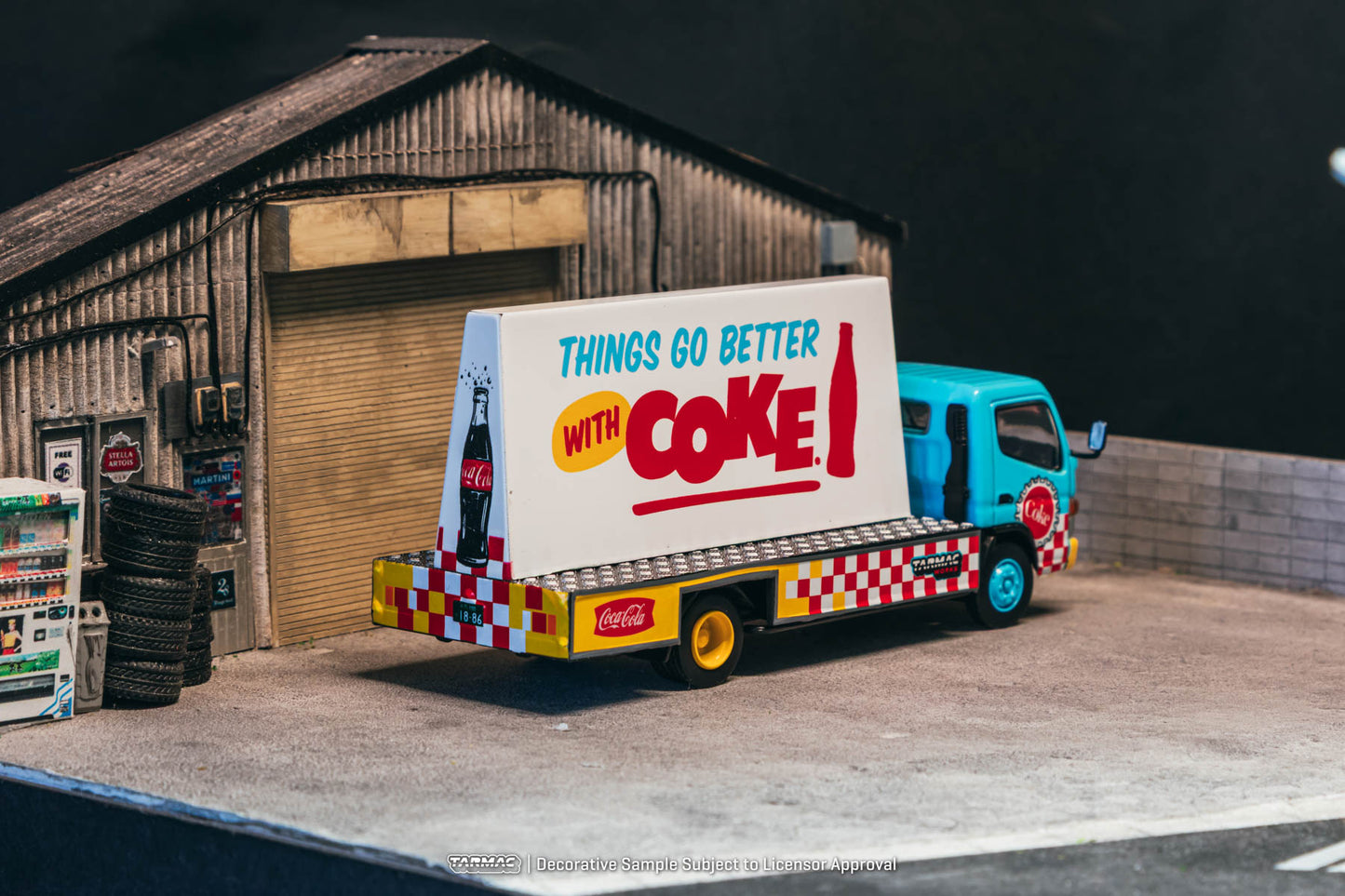 Model Coca-Cola truck in front of a wooden building with 'Things go better with Coke!' sign.