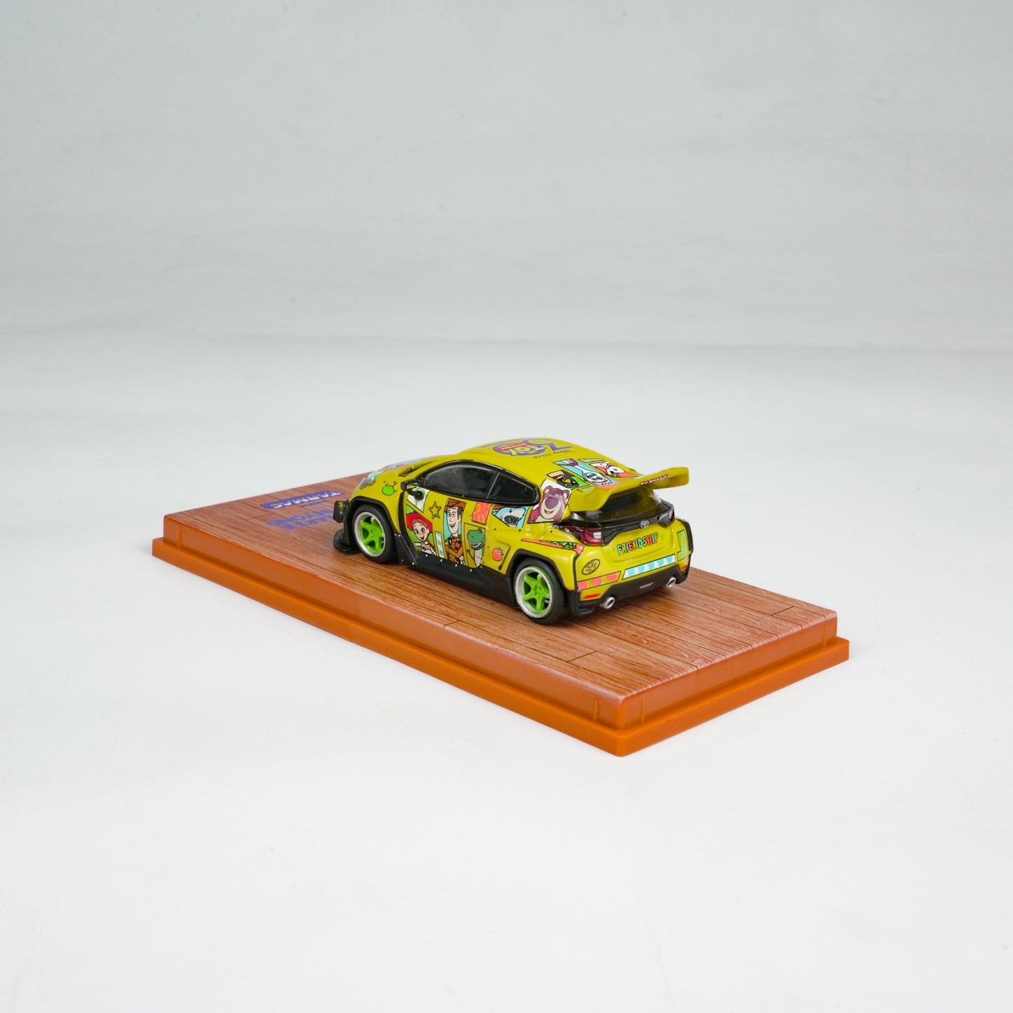 Model car with colorful design on a wooden platform against a light gray background