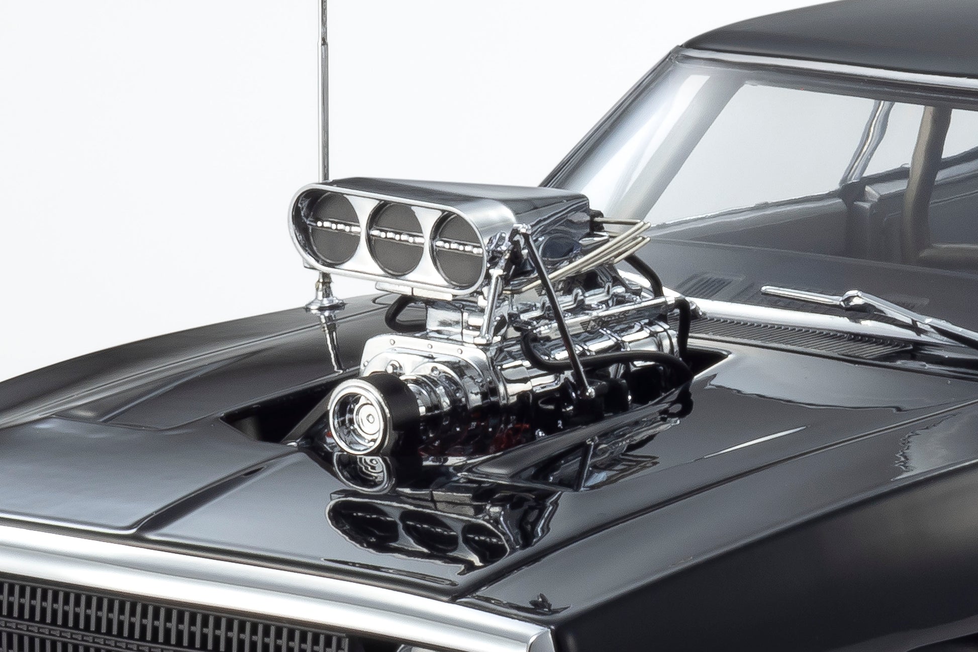 Close-up of a car engine with chrome details on a black car hood.