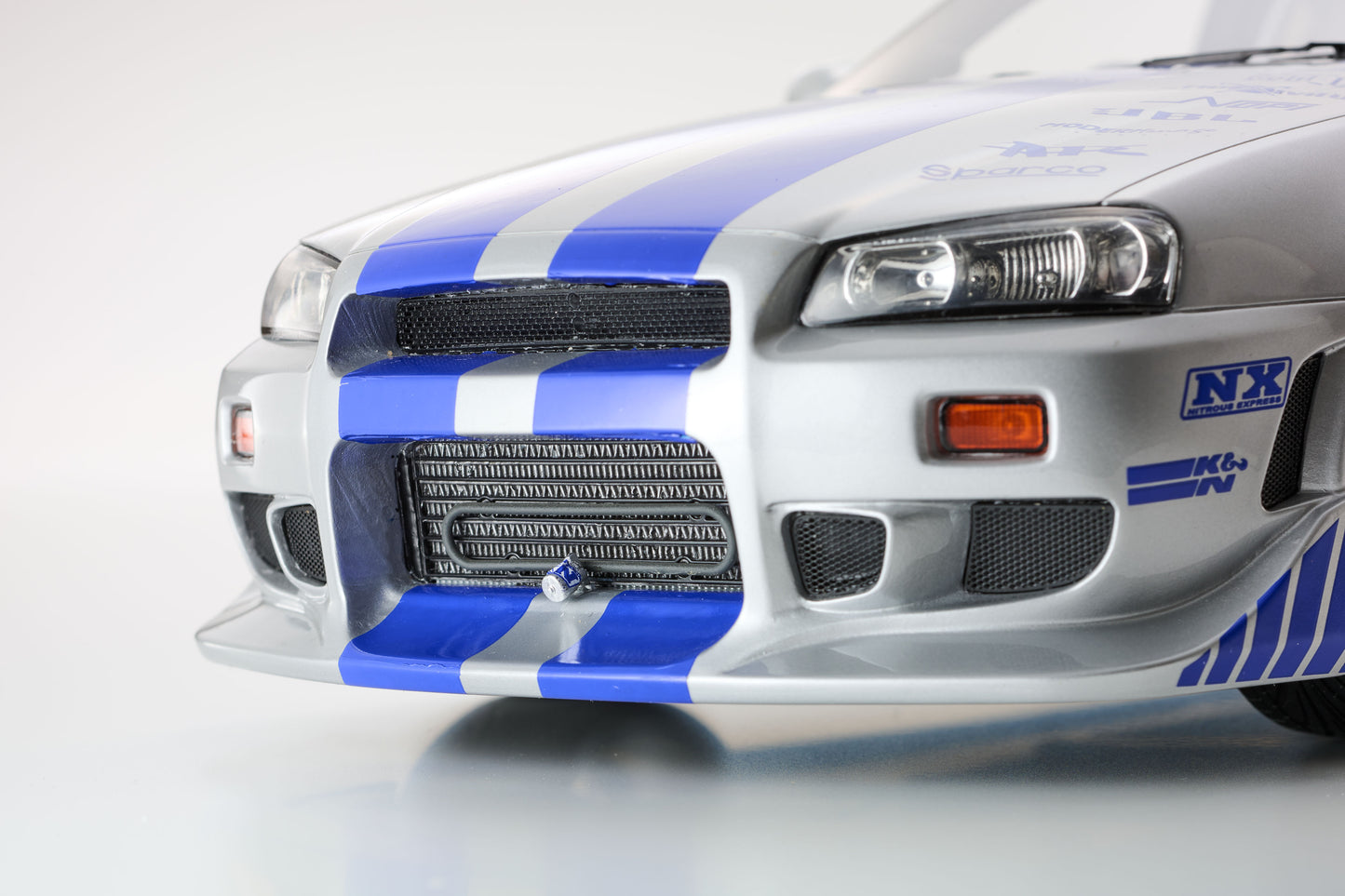 Close-up of a white car with blue and black stripes on a gray background