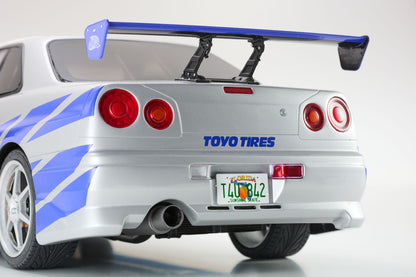 Back view of a silver car with a blue spoiler and Toyo Tires branding on a white background