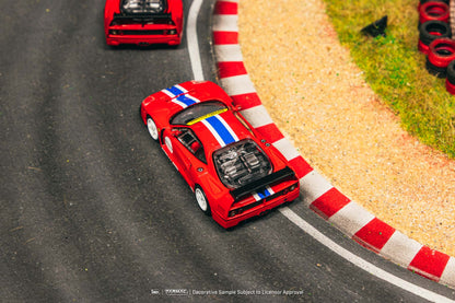Red toy car with a striped design on a track with red and white striped barriers.