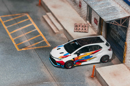 Model car with colorful design on a miniature parking lot and building setup