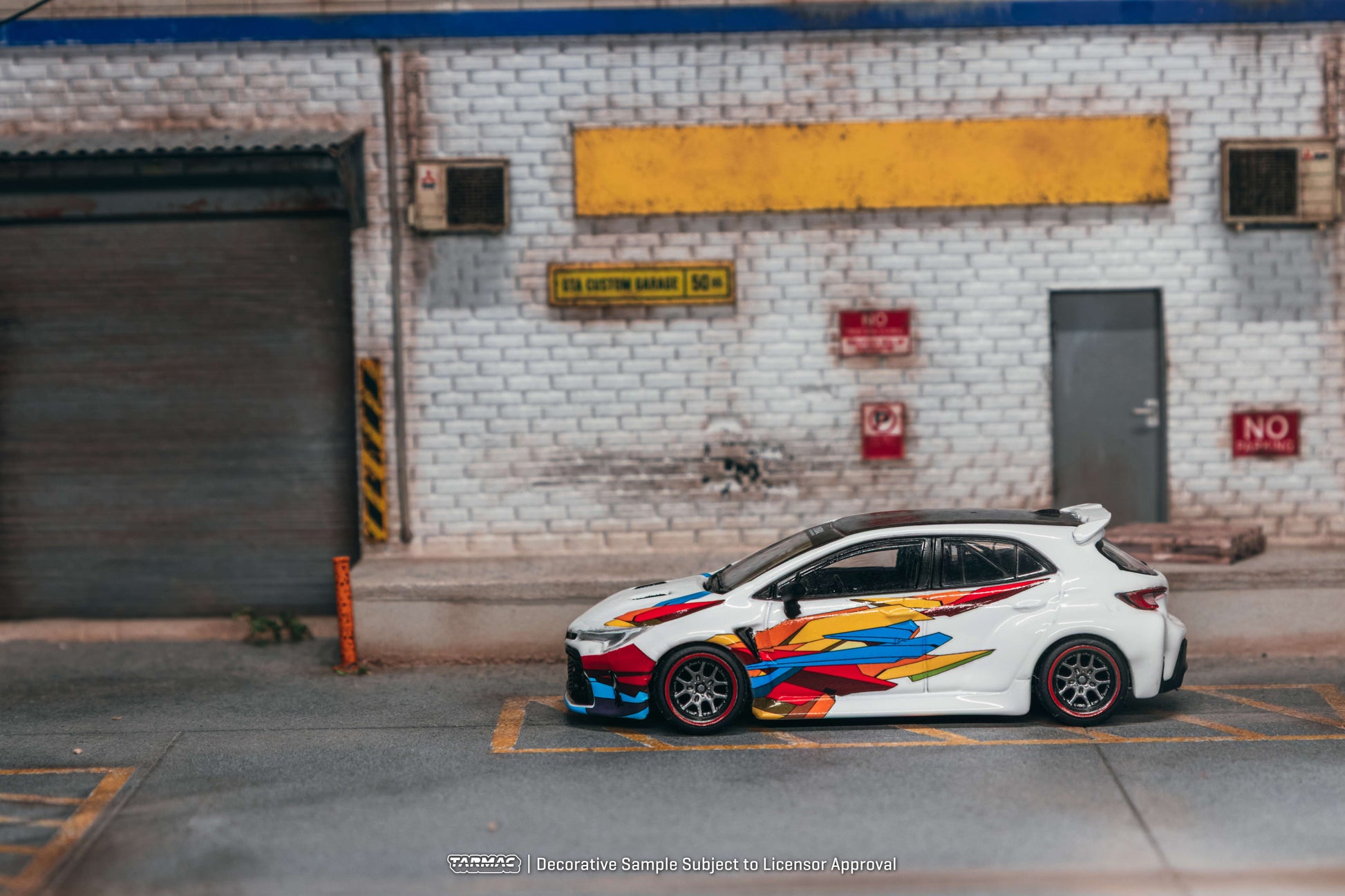 Colorful car parked in front of a brick building with industrial elements.