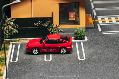 Red car parked in a parking space with a building in the background