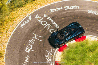 Blue sports car on a winding road with graffiti on the asphalt