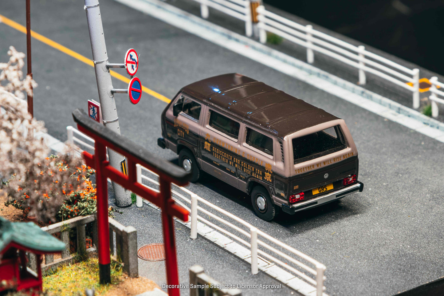 Model van on a miniature road with traffic signs and a Torii gate in the background
