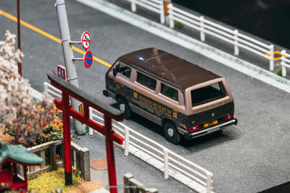 Model van on a miniature road with traffic signs and a Torii gate in the background