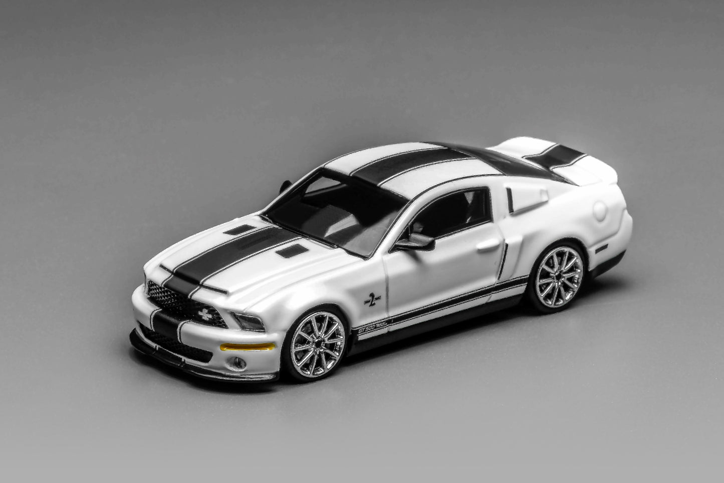White Ford Mustang GT500 model car with black stripes on a gray background