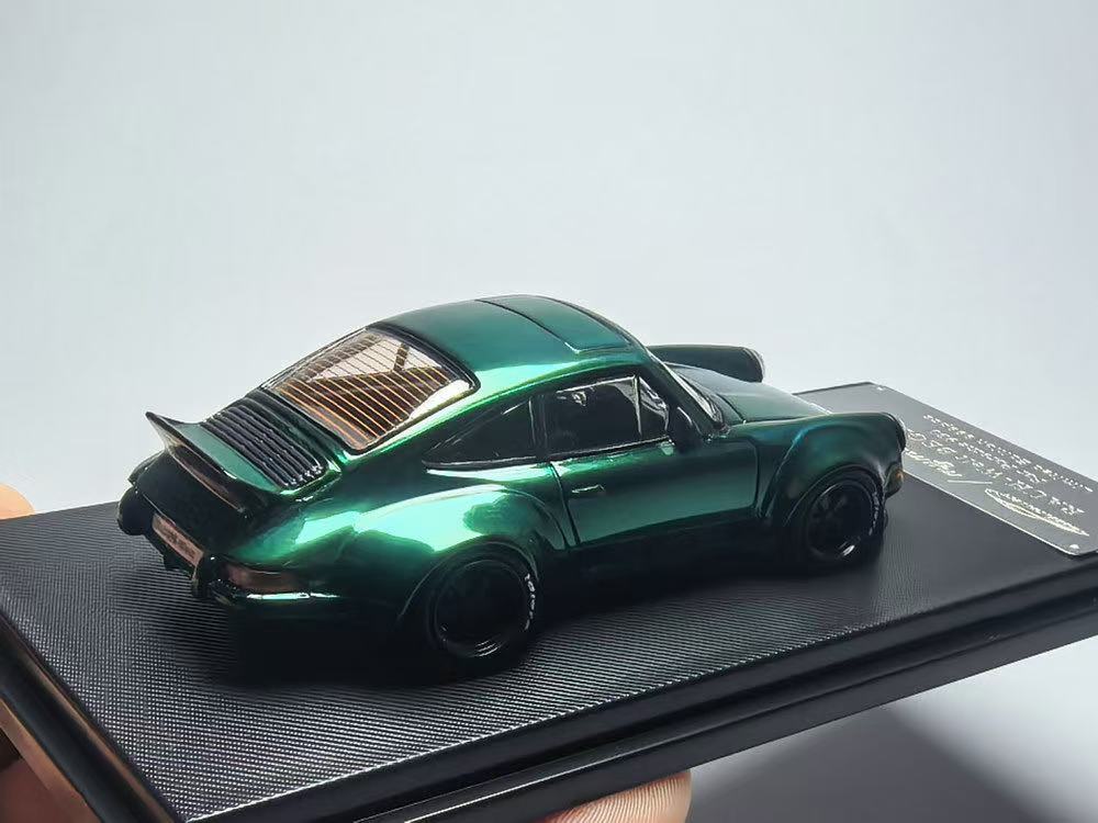 Green model car on a black display stand with a gray background