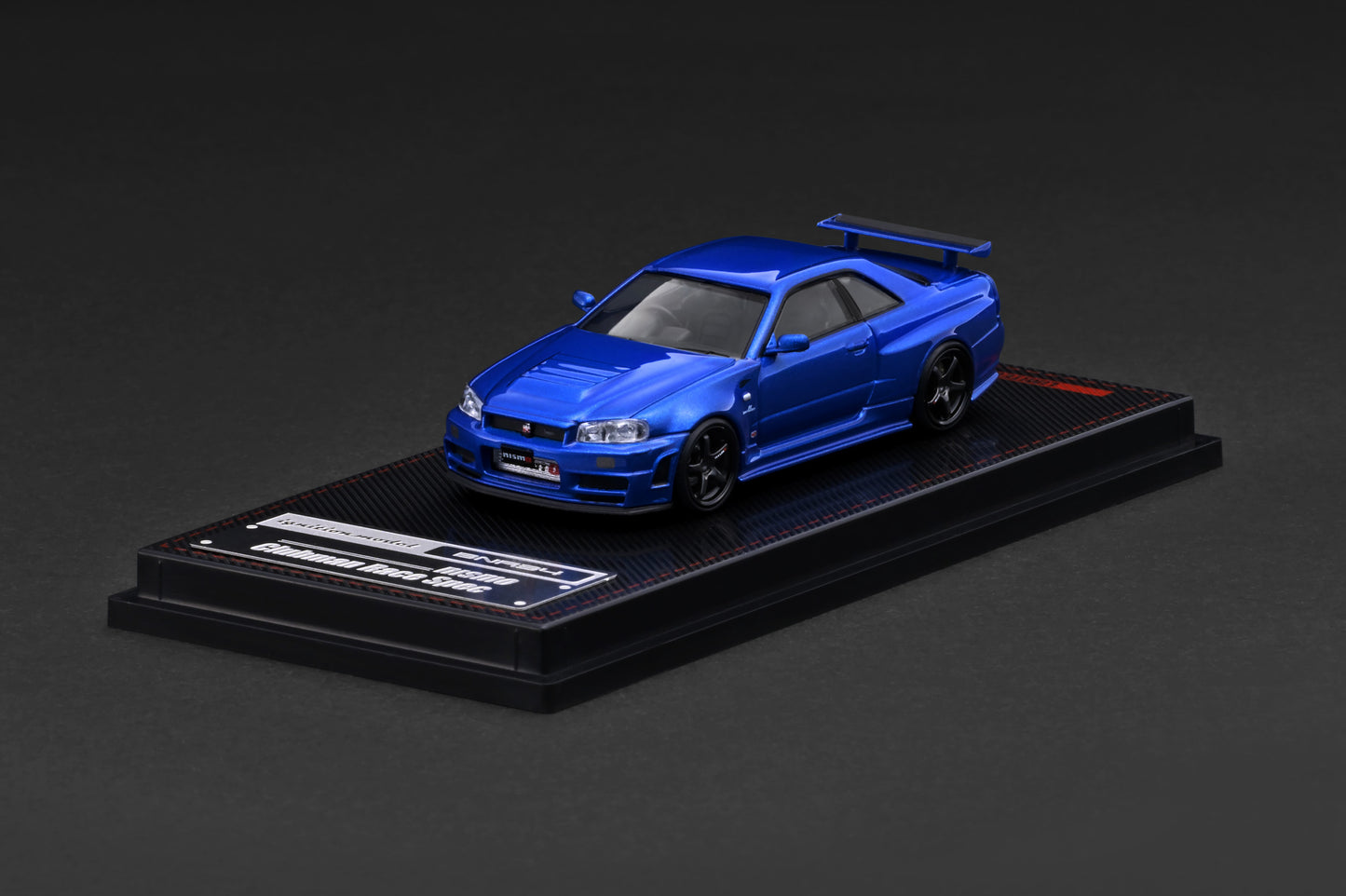 Blue model car on a black display stand against a dark background