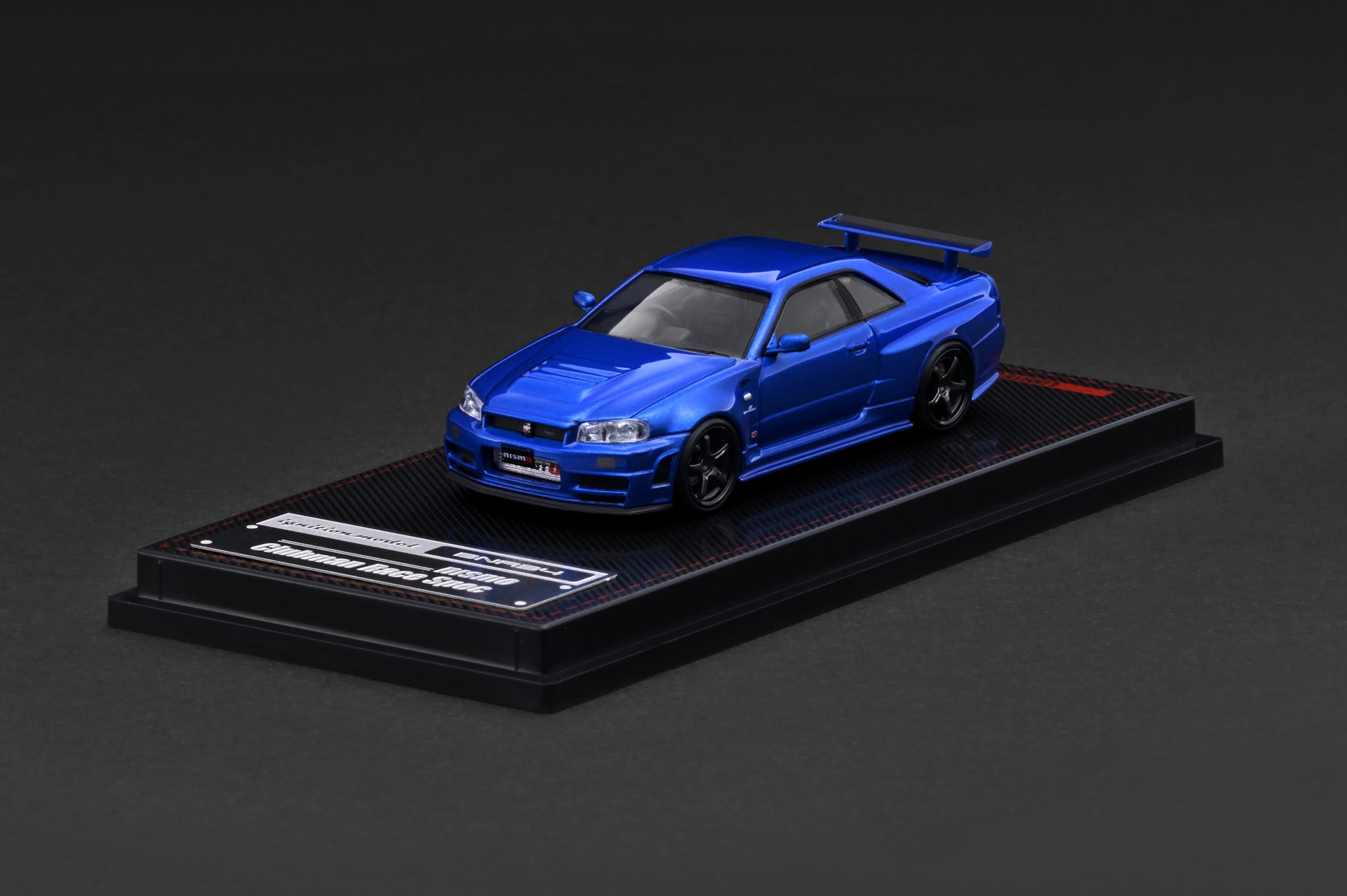 Blue model car on a black display stand against a dark background