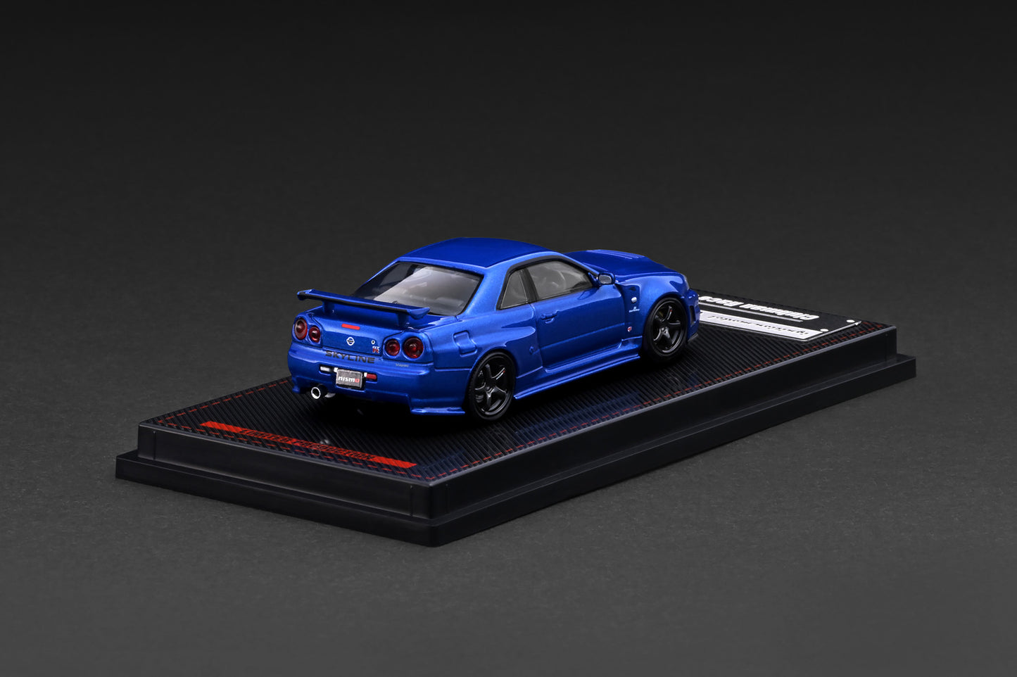 Blue model car on a black display stand against a dark background