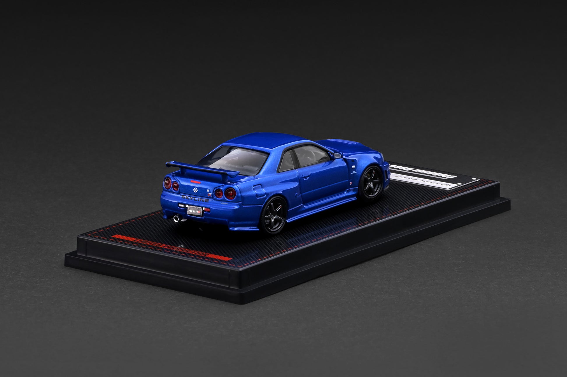 Blue model car on a black display stand against a dark background