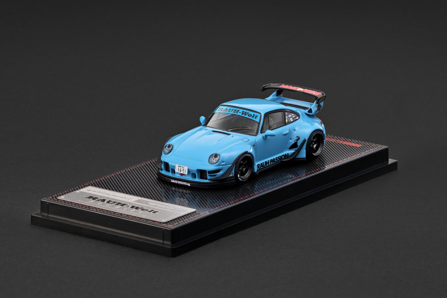 Blue model car on a black display stand with a dark background