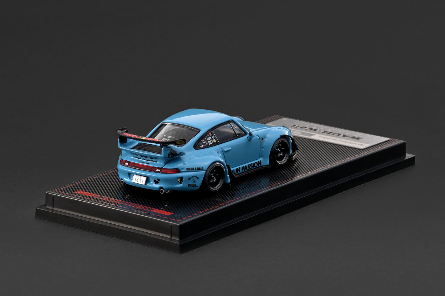 Blue model car on a black display stand with a dark background