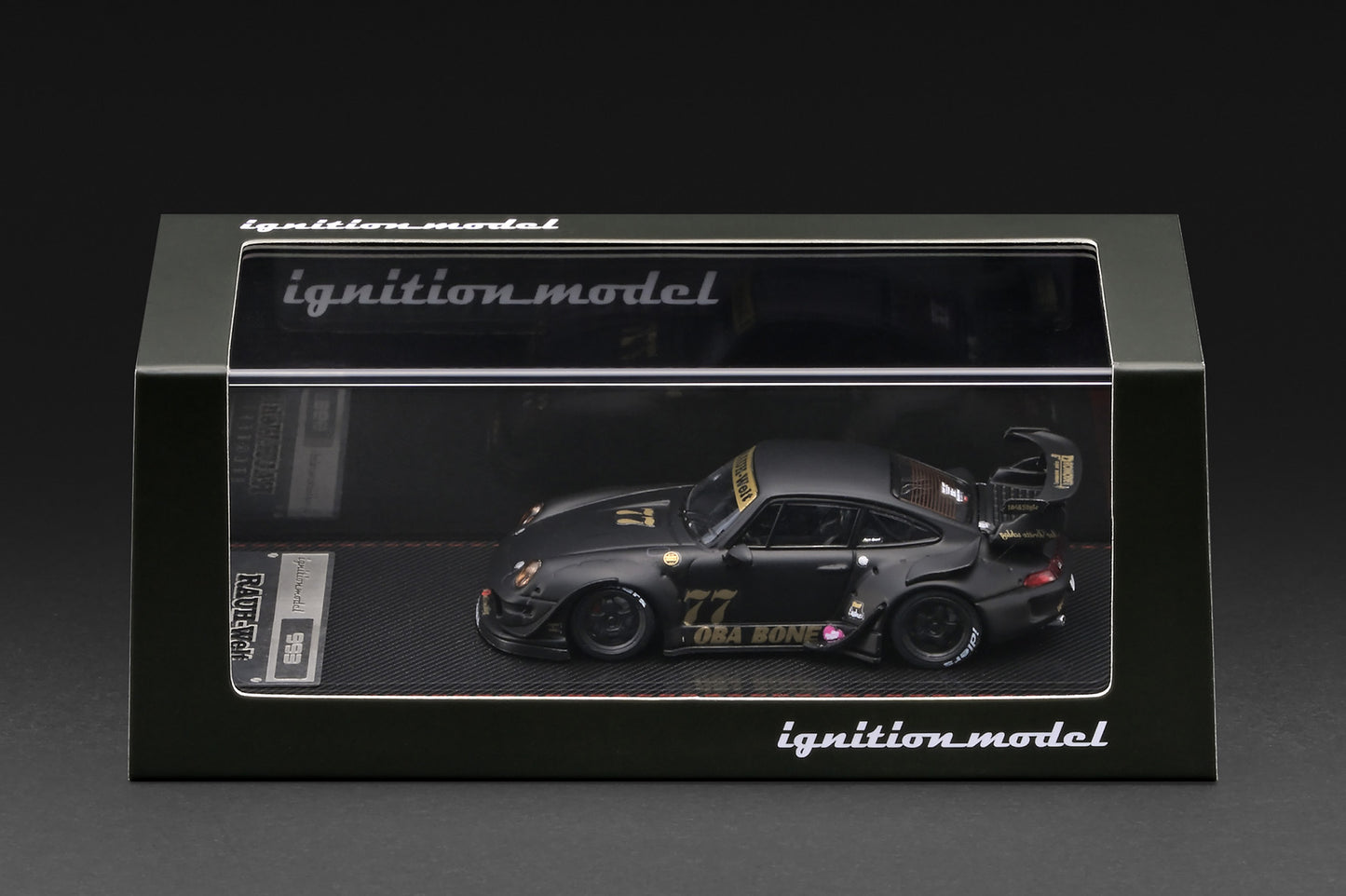 A 1:64 scale model car of the 1999 Toyota 993 RWD Nismo GT1, driven by Ori Bono, displayed inside its black Ignition Model packaging box against a dark background.