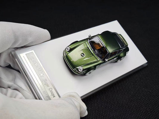 Green model car on an open book held by a gloved hand