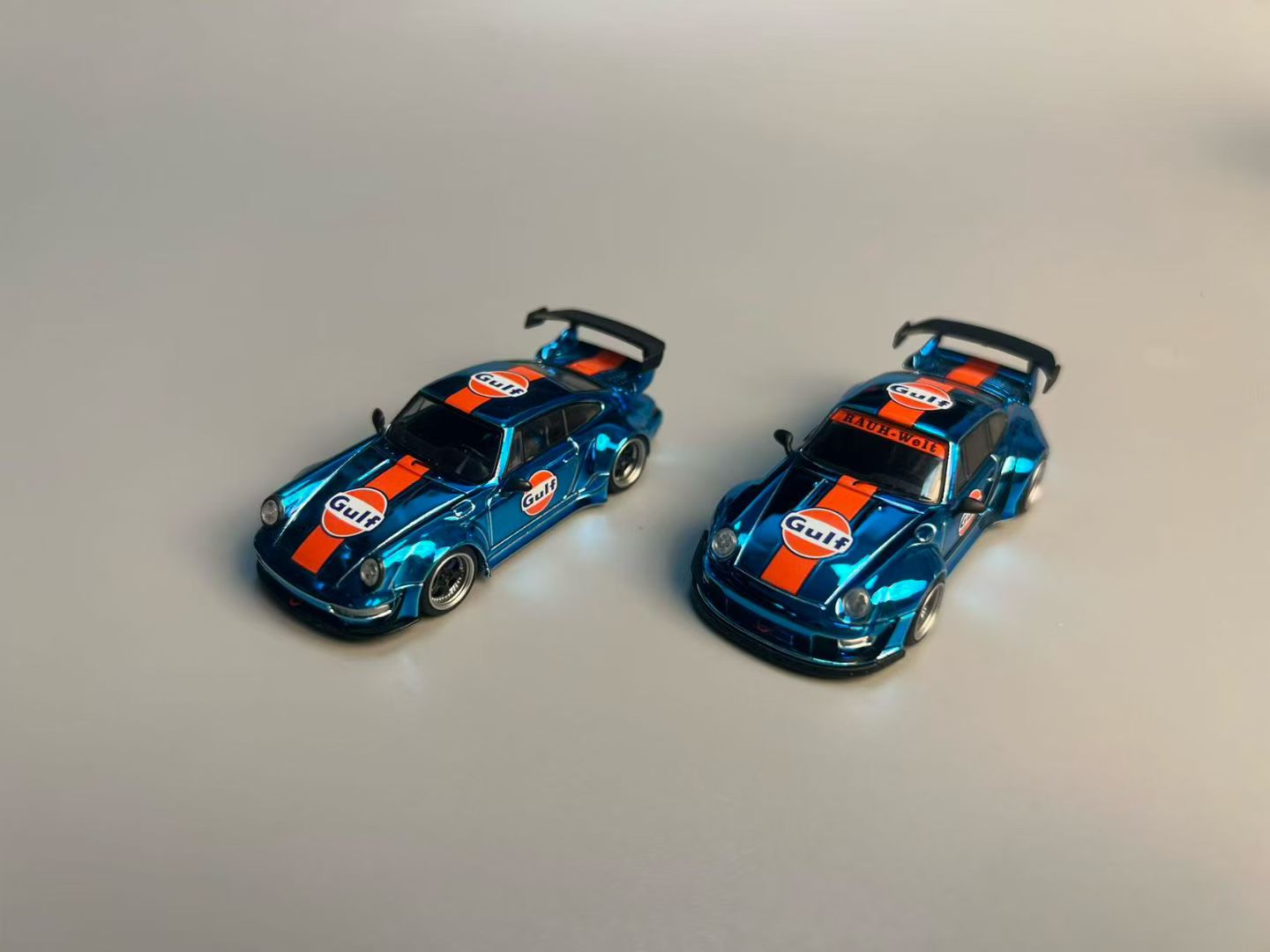 Two blue model cars with orange and white Gulf logos on a gray background