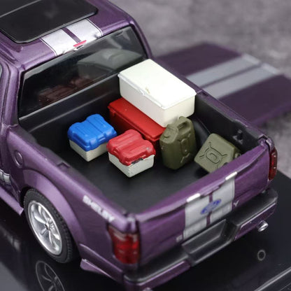 Model truck with open bed containing colorful storage boxes on a reflective surface.
