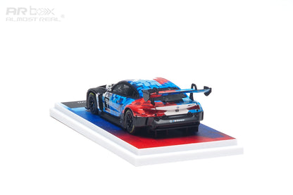 AR Box 1:64 BMW M4 GT3 EVO #1 BMW M Motorsport Racing Livery Diecast Model Car Rear Three Quarter View with Blue Red White Camouflage Graphics, Large Rear Wing, Black Racing Wheels and Display Base